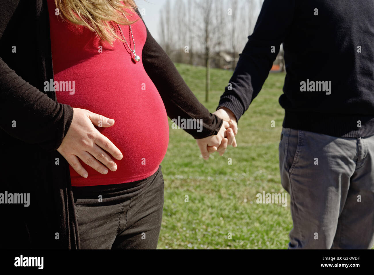 Pregnant couple walking in park Stock Photo