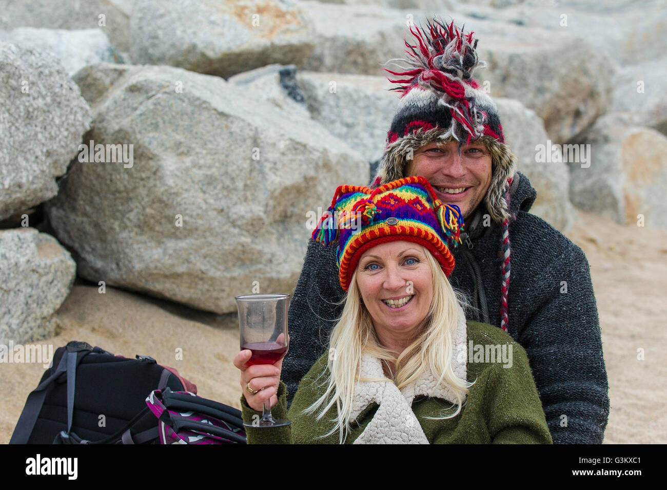 Two holidaymakers keeping warm on a cold and chilly Fistral Beach in Newquay, Cornwall. Stock Photo