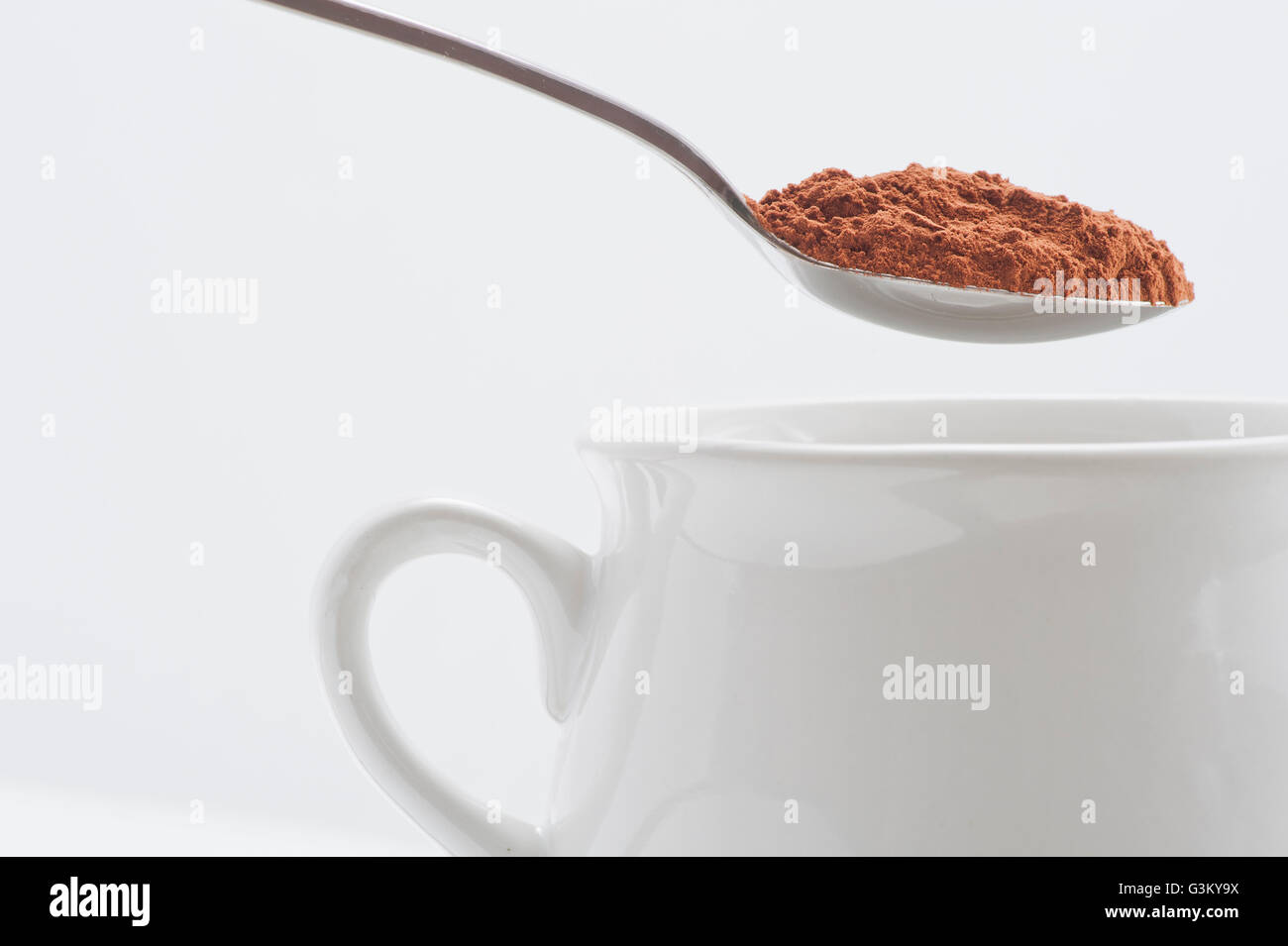 White cup and spoon with cocoa powder Stock Photo