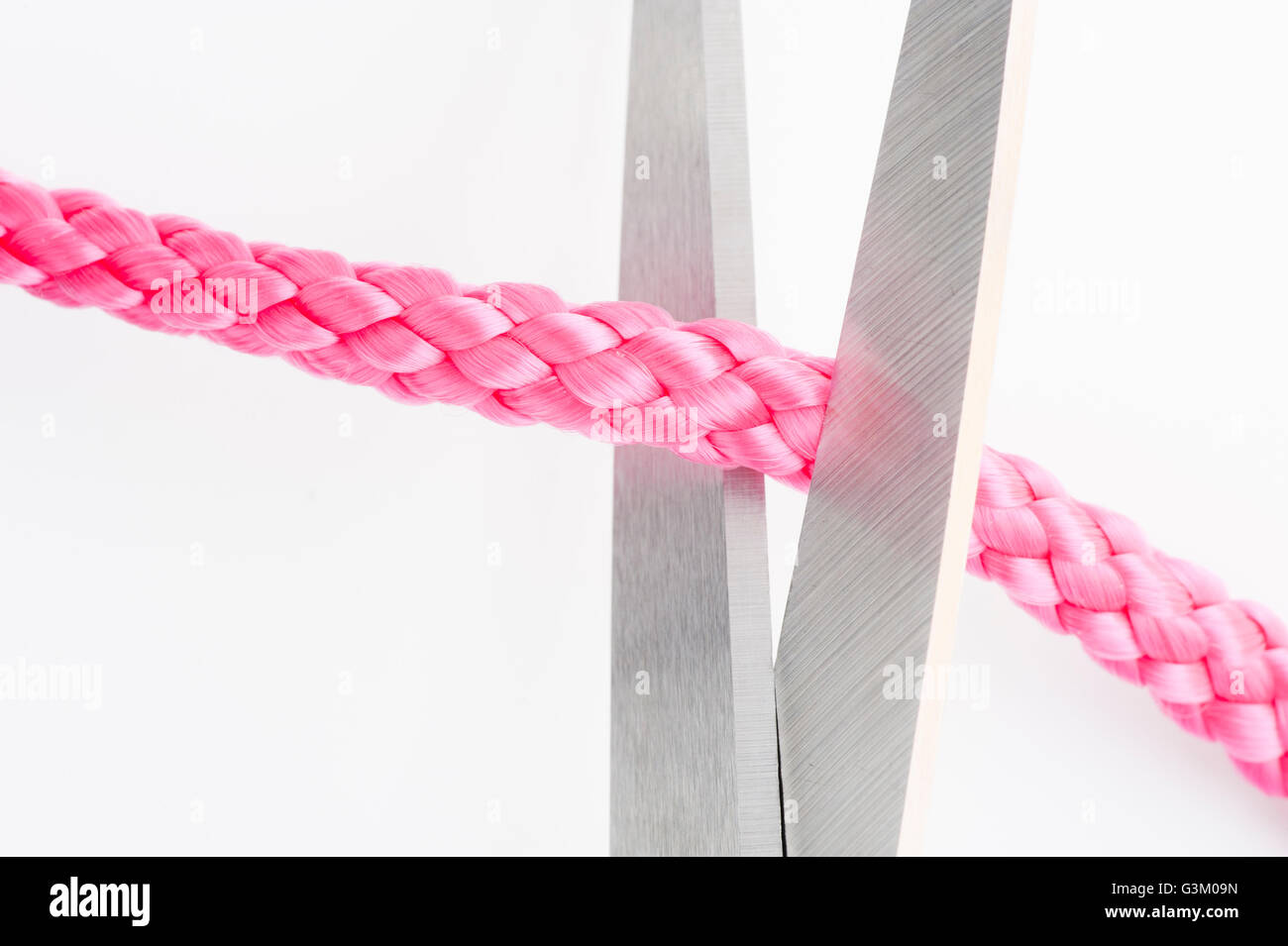 Scissors cutting a pink string Stock Photo