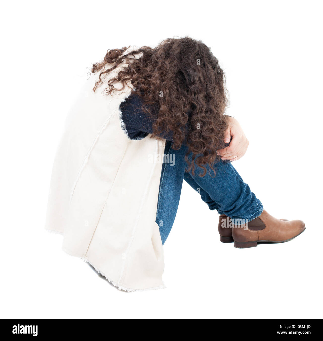 back view curly girl sitting and crying. girl relaxes. Rear view people collection. backside view of person. Isolated over white background. A girl in a white tank top sitting on the floor with his head resting on his legs. Stock Photo