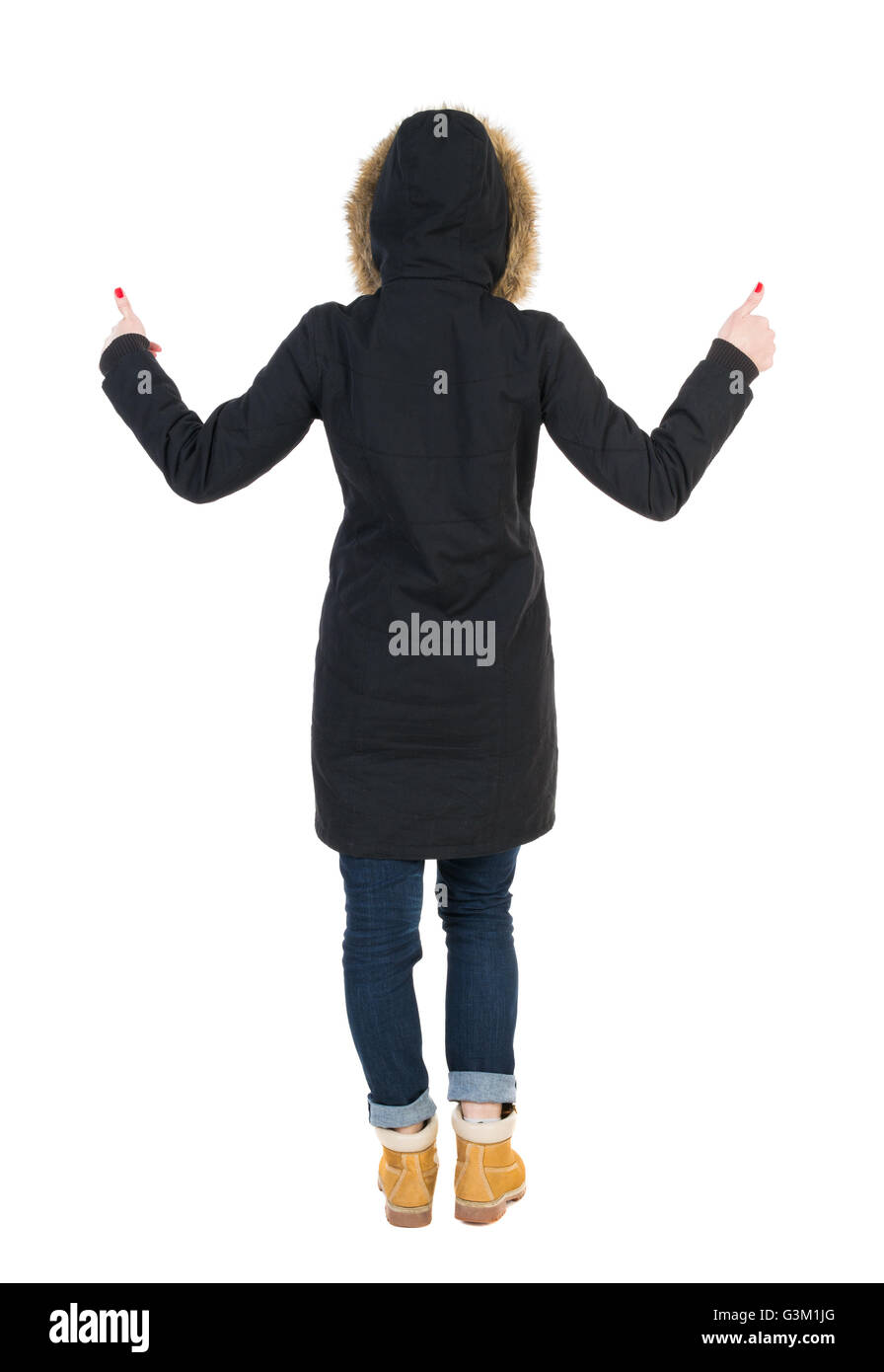 Back view of woman in parka thumbs up. Rear view people collection.  backside view of person. Isolated over white background. Girl in a black  winter jacket with a hood with two hands