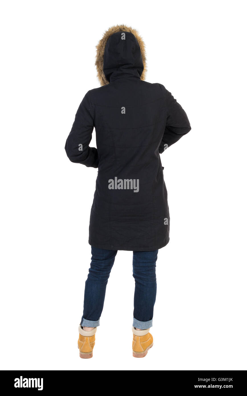 Back view woman in winter jacket looking up. Standing young girl in parka. Rear view people collection. backside view of person. Isolated over white background. Girl in a black winter jacket with a hood to hide his hands in his pockets Stock Photo