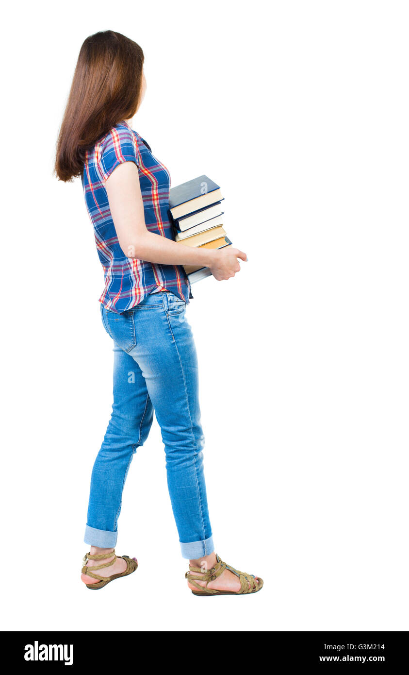 A girl carries a heavy pile of books. side view. Rear view people collection. backside view of person. Isolated over white background. A young girl in a checkered blue with red stripes stands sideways and holding a stack of college textbooks. Stock Photo