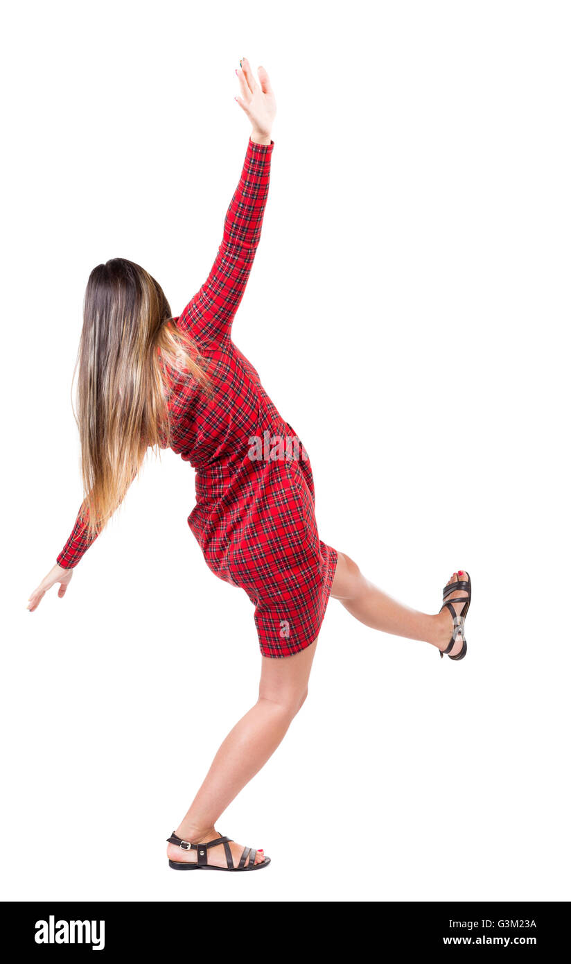 Balancing young woman. or dodge falling woman. Rear view people collection. backside view of person. Isolated over white background. The girl in red plaid dress balances trying not to fall. Stock Photo