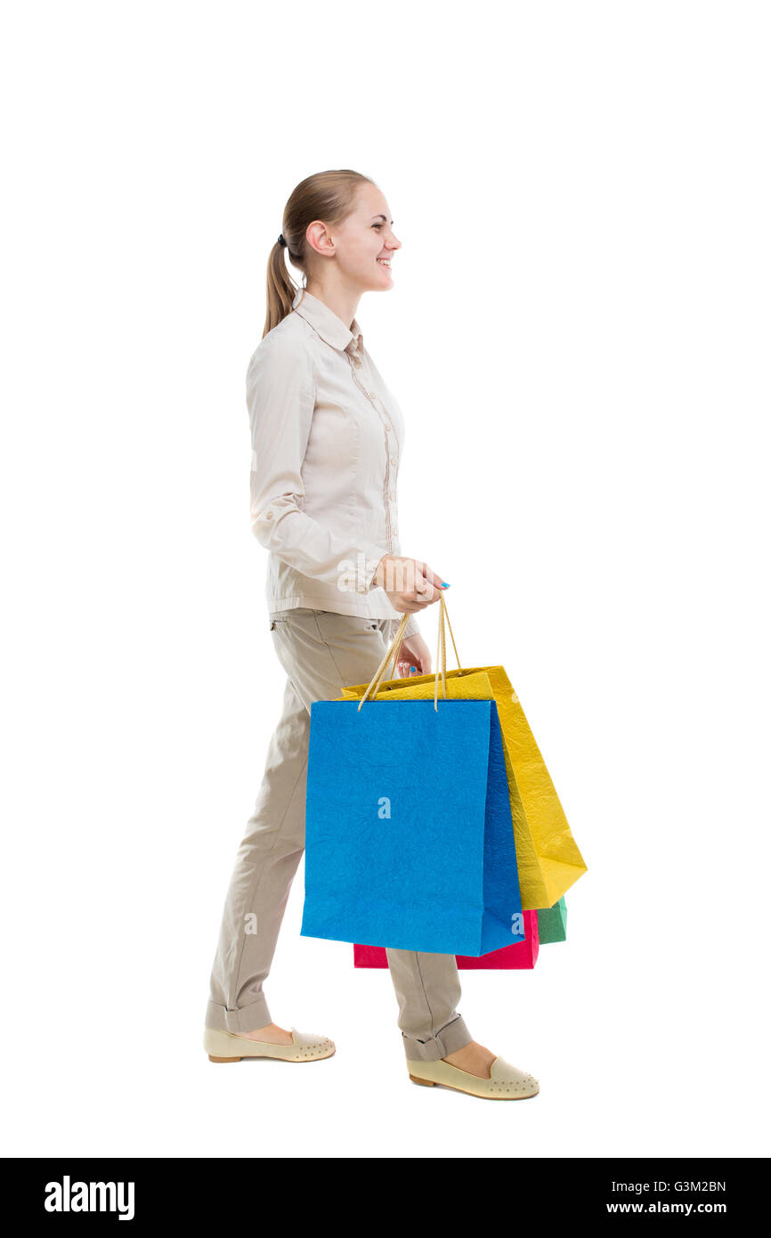back view of going woman with shopping bags . beautiful girl in motion. backside view of person. Rear view people collection. Isolated over white background. Girl in gray jeans goes away smiling and carries a handbag. Stock Photo