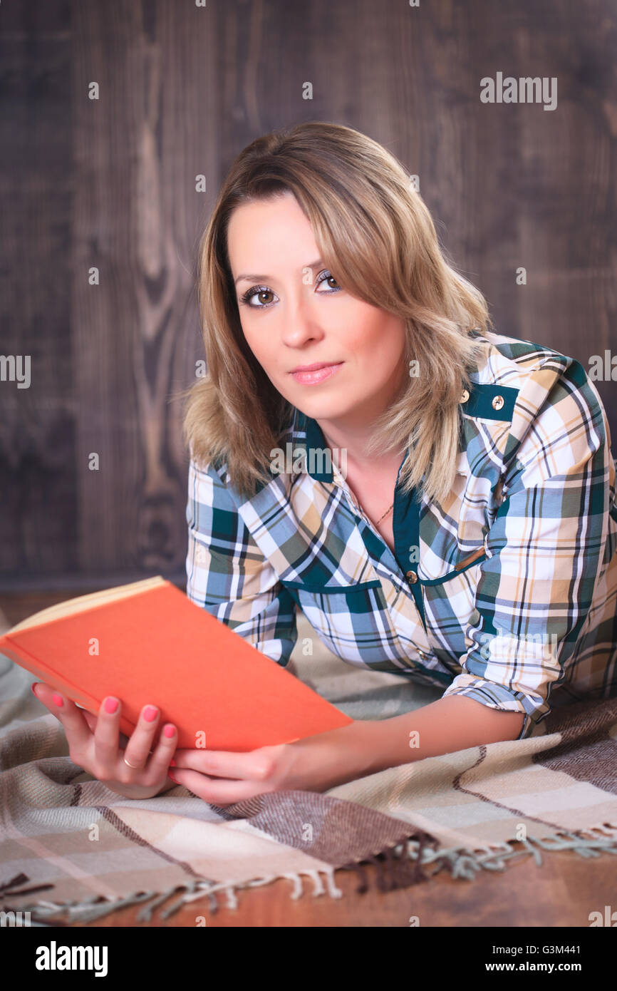 Young cute woman reading a book lying on a plaid Stock Photo