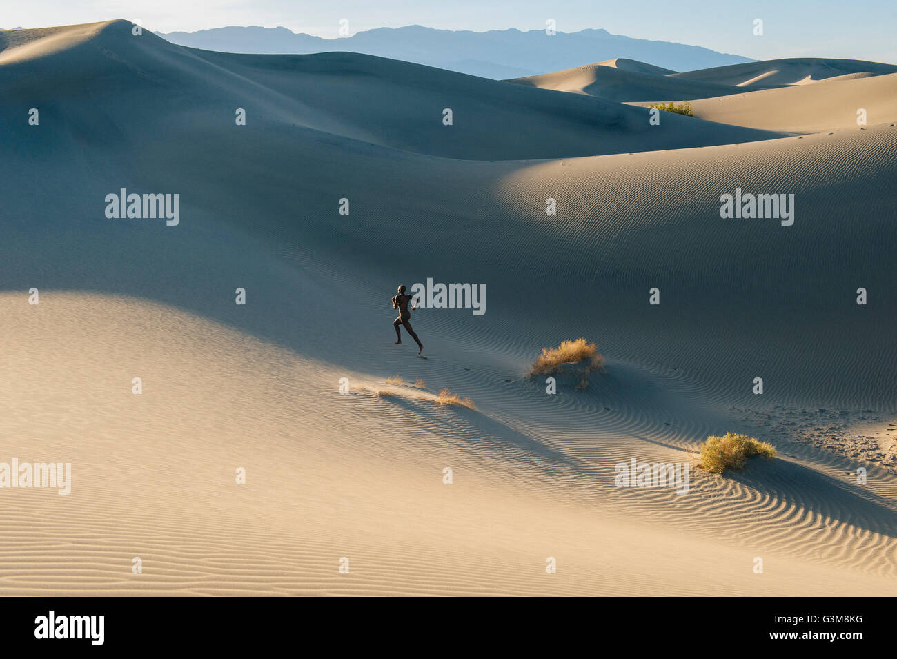 Nude woman in desert running up dune Stock Photo