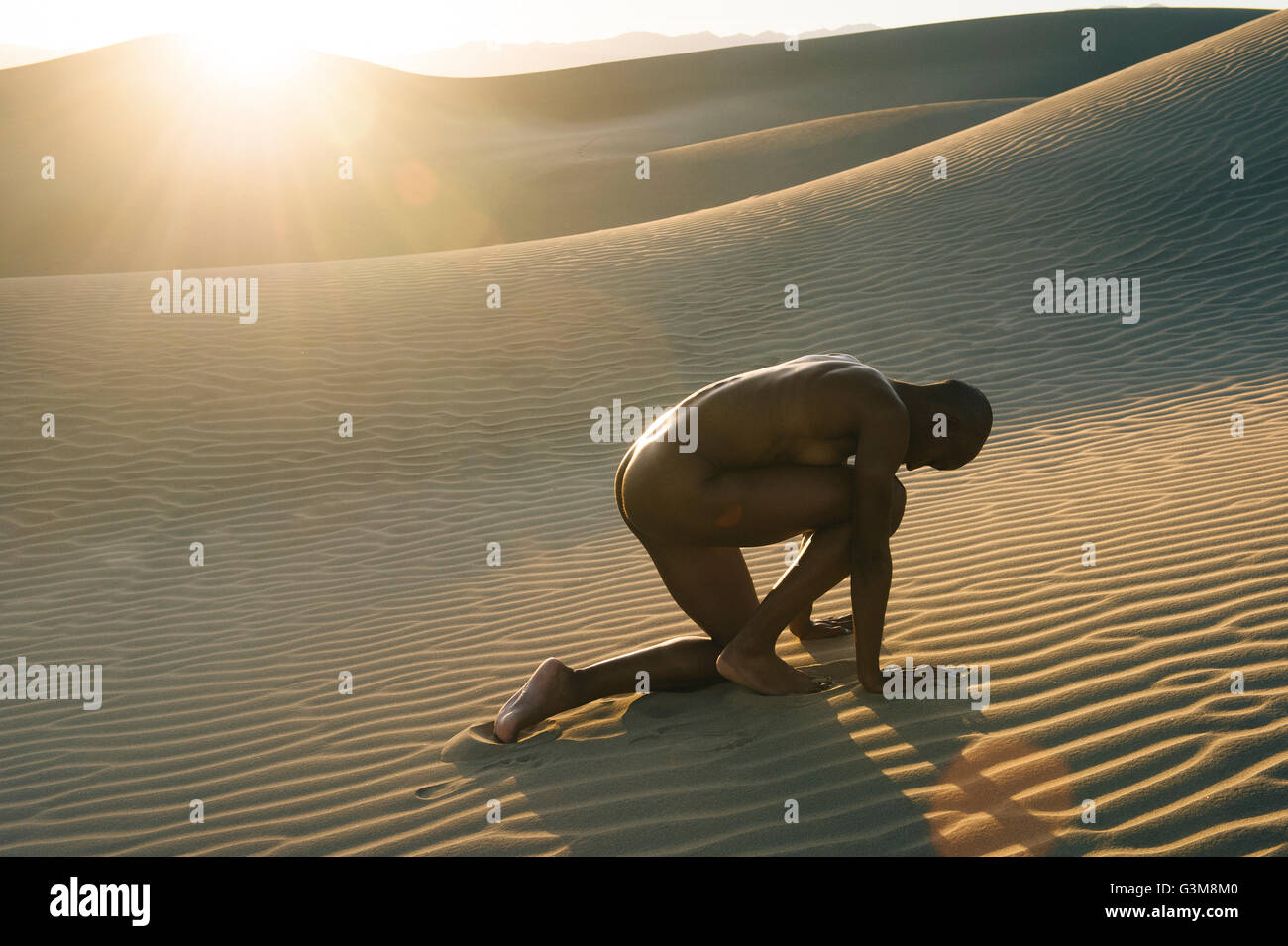 Nude woman crouched in the desert Stock Photo