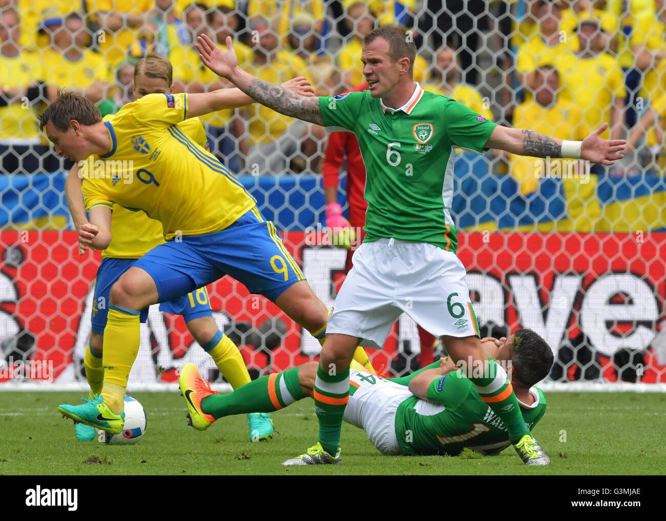 St. Denis, France. 13th June, 2016. Kim Kallstrom (L) of Sweden vies for the ball with Glenn Whelan (R) of Irland while Jonathan Walters lies on the pitch during the Group E soccer match of the UEFA EURO 2016 between Ireland and Sweden at the Stade de France in St. Denis, France, 13 June 2016. Photo: Peter Kneffel/dpa/Alamy Live News Stock Photo