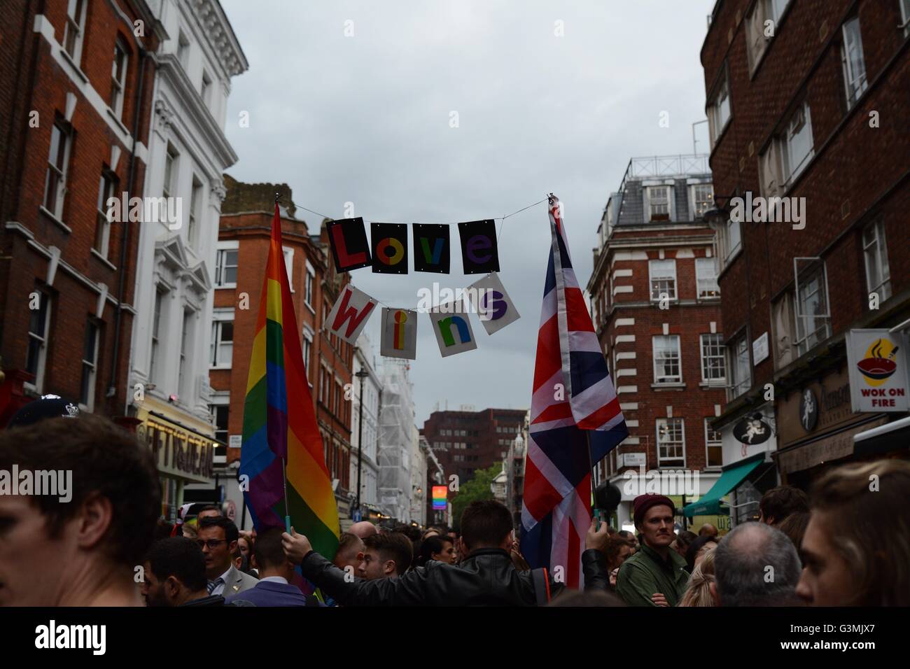 London, UK. June 13th 2016. A mourner holds a sign saying 'Love Wins' with a projection of the rainbow flag downstreet. Credit: Marc Ward/Alamy Live News Stock Photo