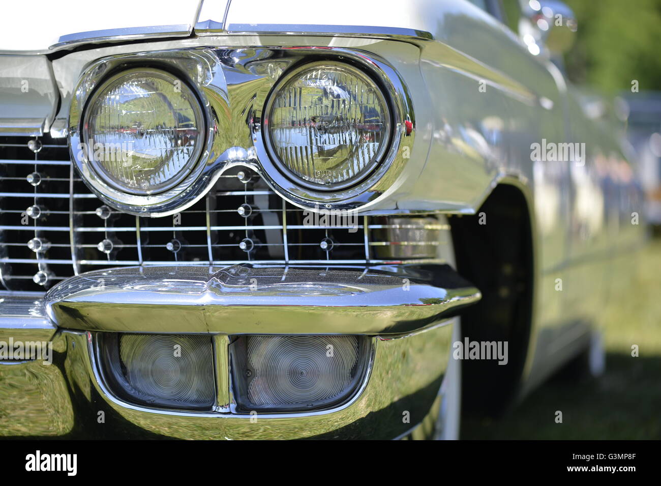 Westbury, New York, USA. June 12, 2016.  Chrome double headlights and running lights are seen in close up of classic1960 white Cadillac sedan on display at the Antique and Collectible Auto Show at the 50th Annual Spring Meet at Old Westbury Gardens, in the Gold Coast of Long Island, and sponsored by Greater New York Region, GNYR, Antique Automobile Club of America, AACA. Participating vehicles in the judged show included hundreds of domestic and foreign, antique, classic, collectible, and modern cars. Stock Photo