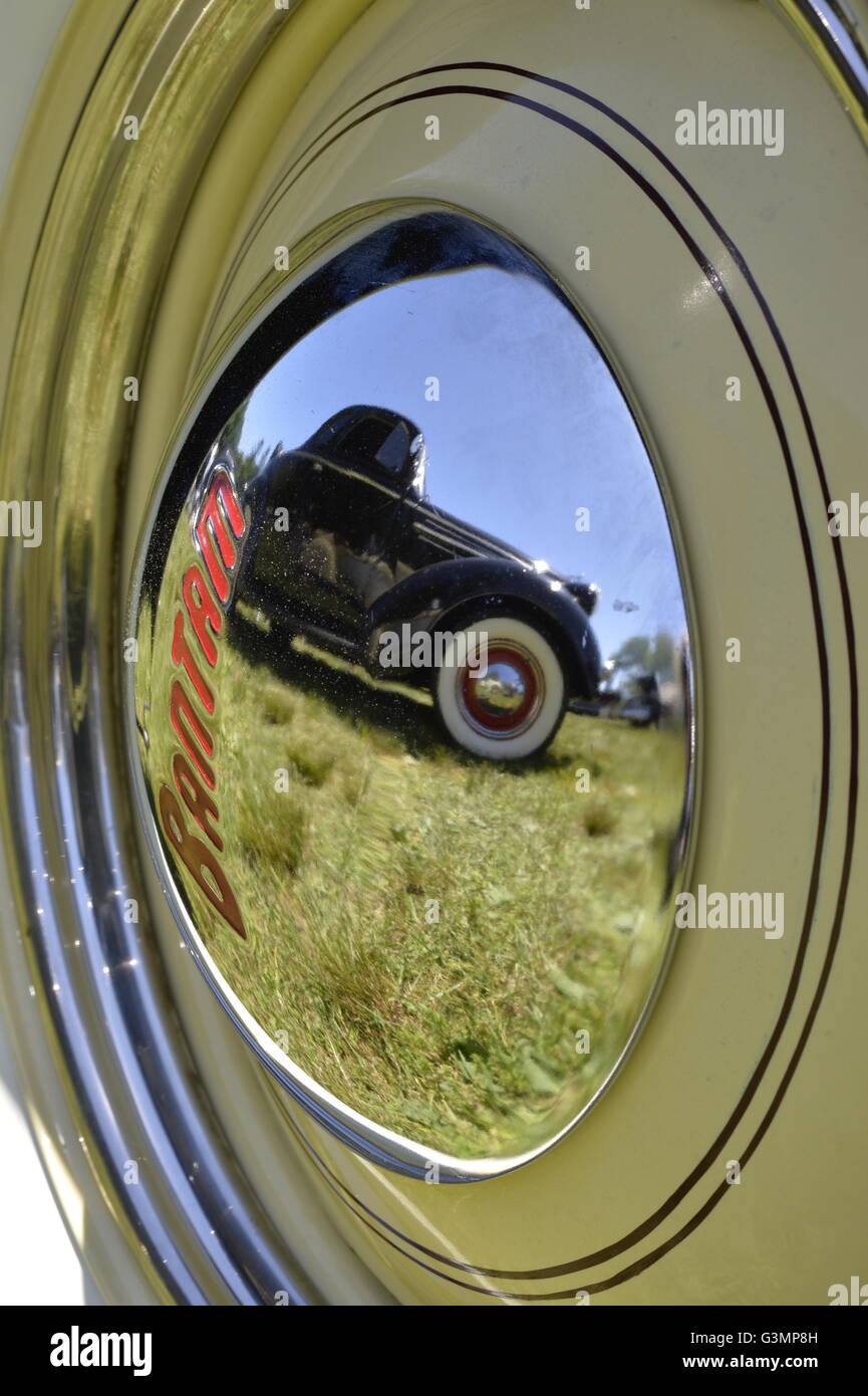 Westbury, New York, USA. June 12, 2016.  A yellow 1948 Bantam Roadster, owned by Wade Jacobs of Mineola, has reflection of nearby vintage black car on its hubcap, at the Antique and Collectible Auto Show at the 50th Annual Spring Meet at Old Westbury Gardens, in the Gold Coast of Long Island, and sponsored by Greater New York Region, GNYR, Antique Automobile Club of America, AACA. Participating vehicles in the judged show included hundreds of domestic and foreign, antique, classic, collectible, and modern cars. Stock Photo