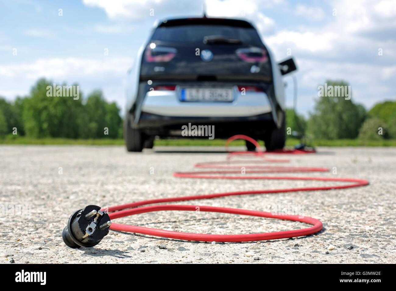 Symbolic image - A red electric cable behind a BMW i3 electric car on a ...