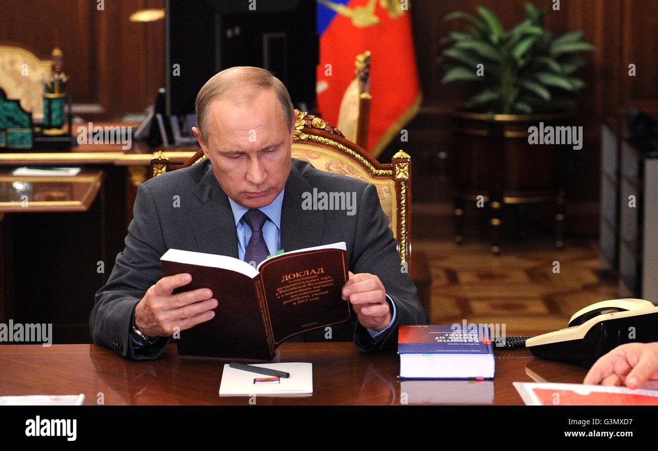 Moscow, Russia. 14th June, 2016. Russian President Vladimir Putin reviews a book during a meeting with President of the Russian Academy of Sciences Vladimir Fortov and Director of the Federal Agency for Scientific Organisations Mikhail Kotyukov at the Kremlin June 14, 2016 in Moscow, Russia. Credit: Planetpix/Alamy Live News Stock Photo