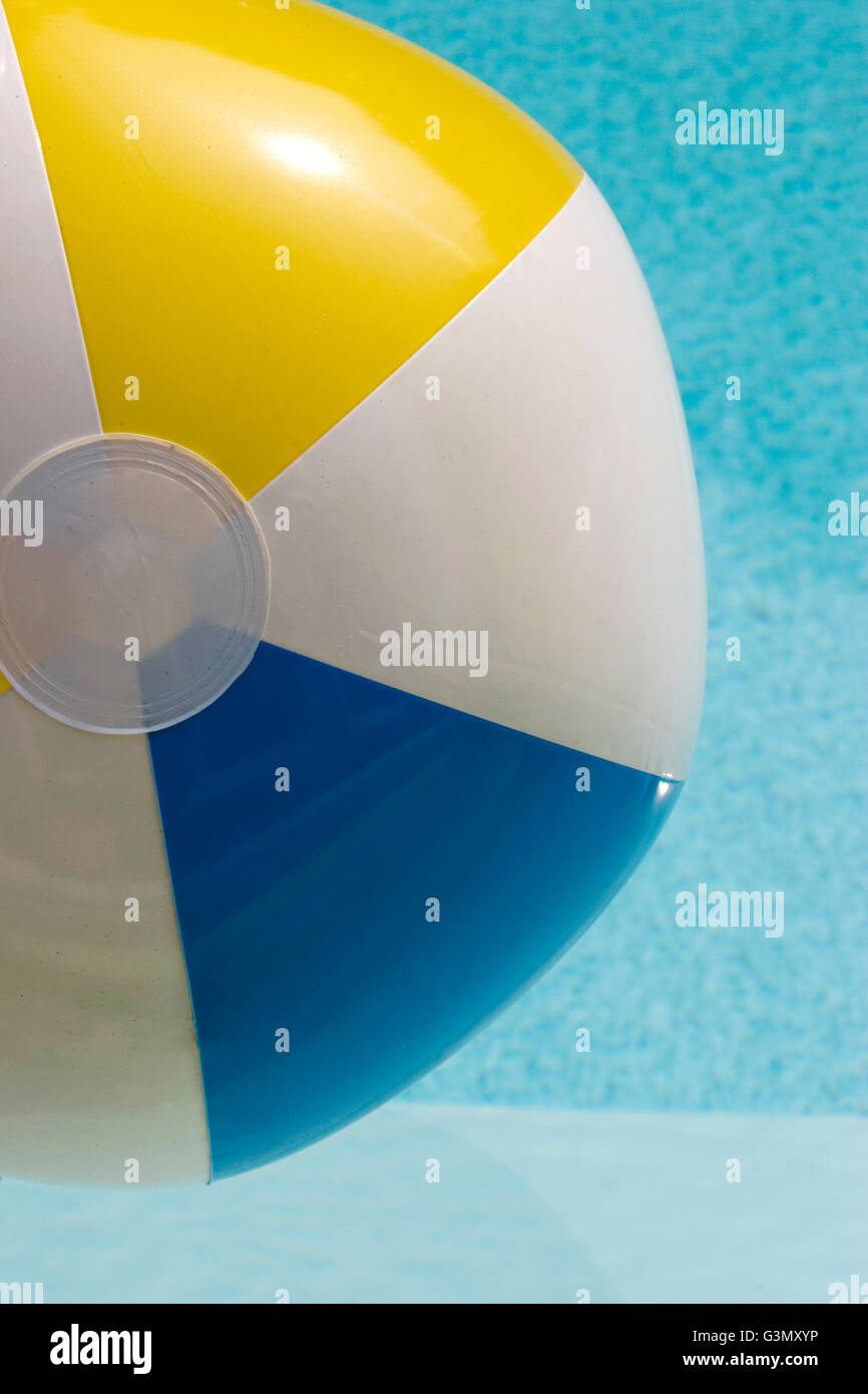 Inflatable blue, white and yellow beach ball in swimming pool Stock Photo