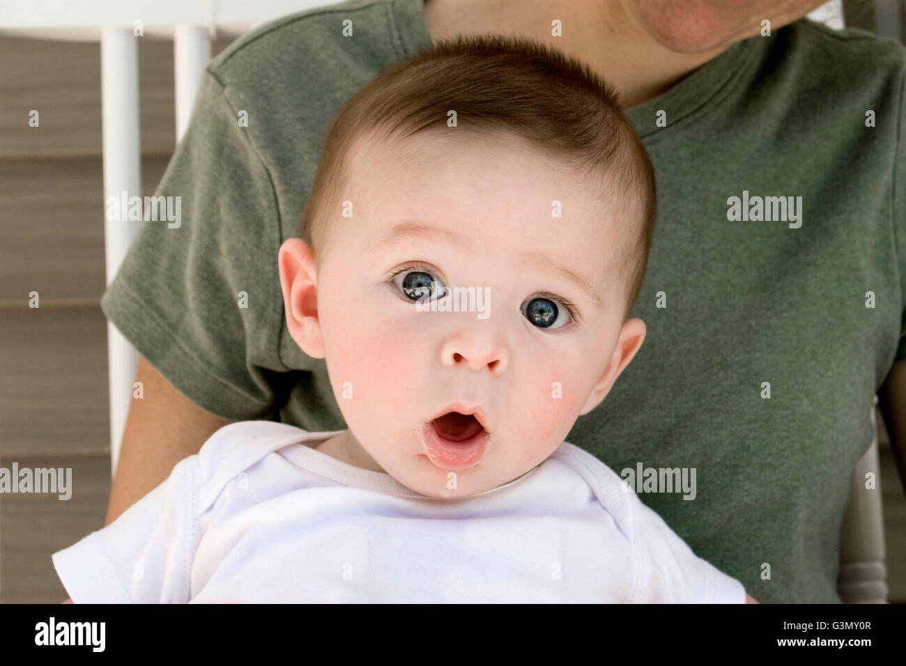 Surprised baby sitting in his Mother's lap Stock Photo