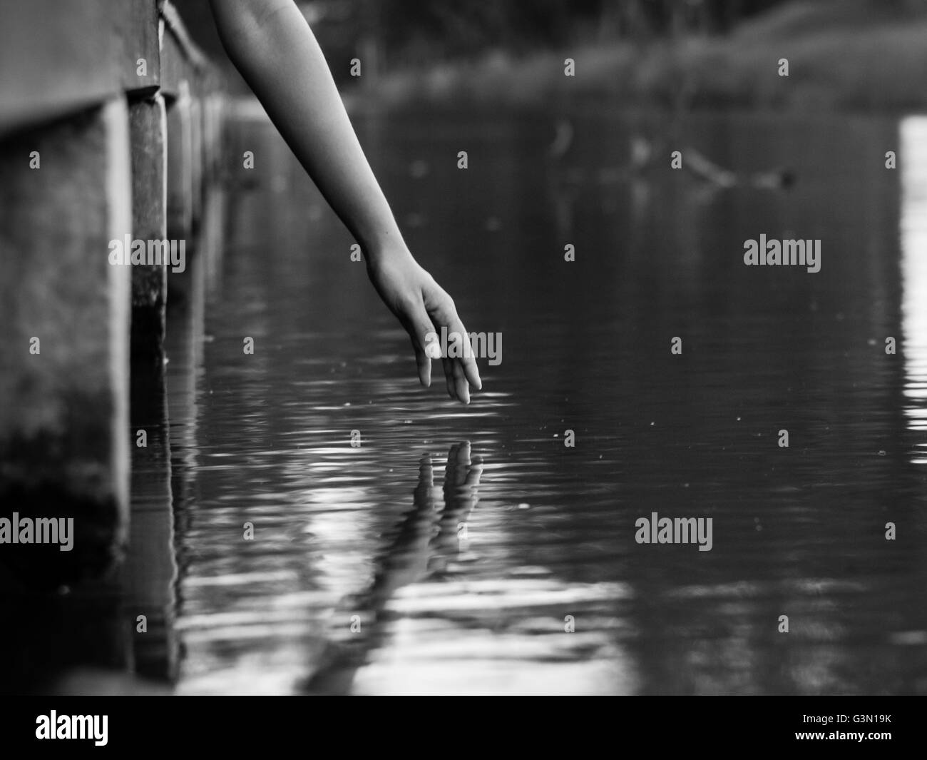 A hand reaching to water surface with reflection Stock Photo