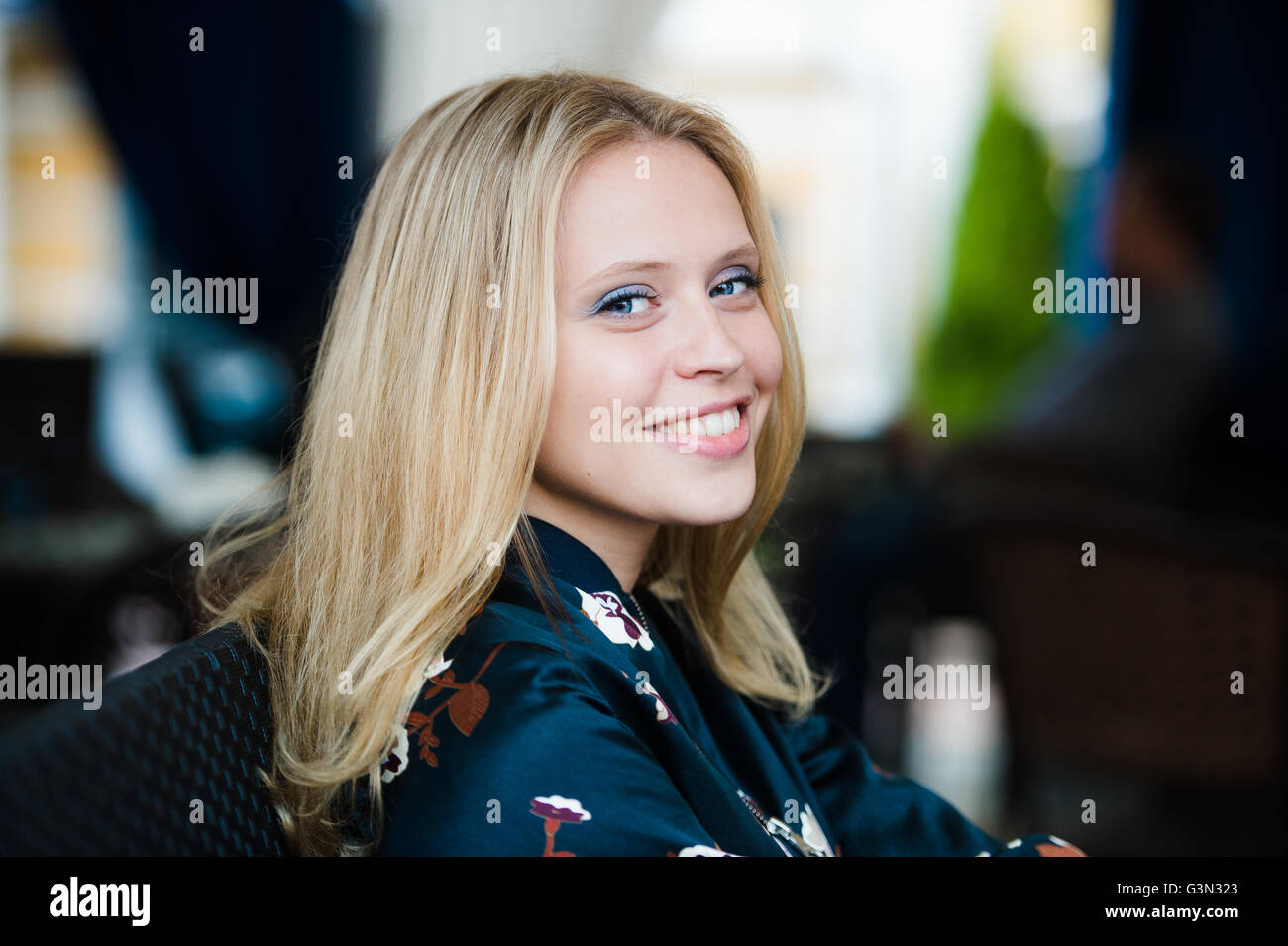 Close up portrait of a young woman's smiling face with outdoors cafe blurred background. Stock Photo
