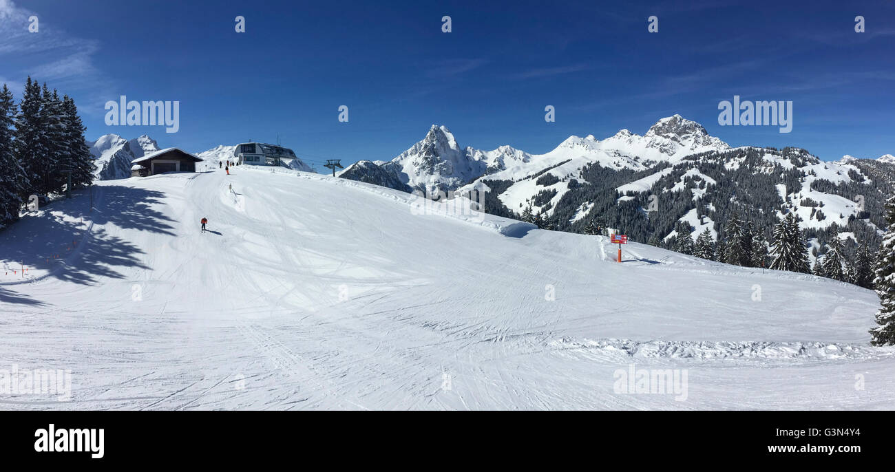 Panoramic view of groomed skiing slopes against a mountain backdrop in the Swiss Alps. Gstaad winter sports area, Switzerland. Stock Photo