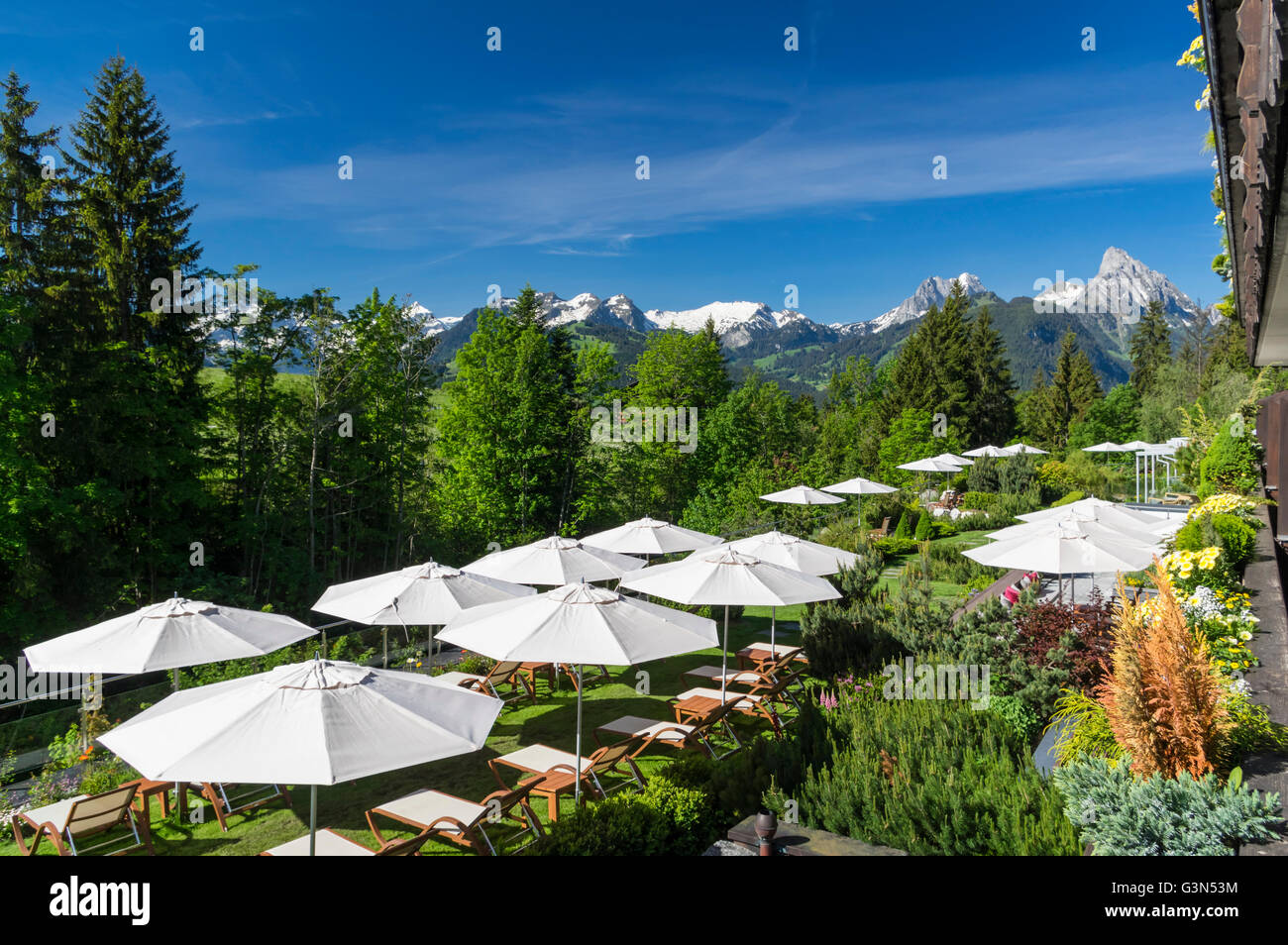 View of the garden of the Ermitage Golf Hotel in Schönried ob Gstaad,  Switzerland. Snowcapped mountains in the background Stock Photo - Alamy