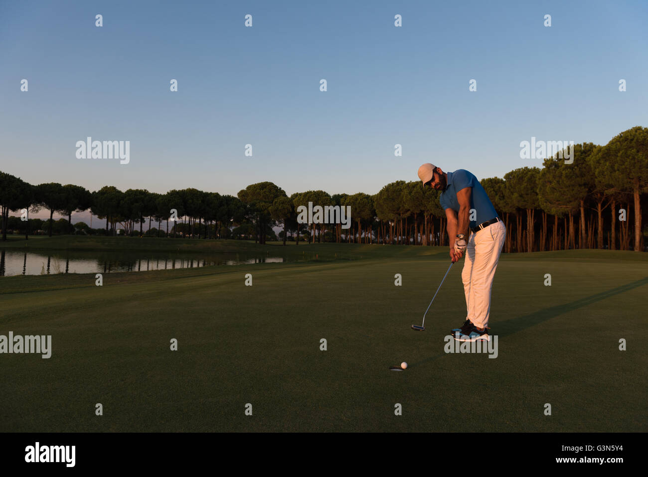 golfer hitting ball shot with driver on golf course at beautiful sunset ...