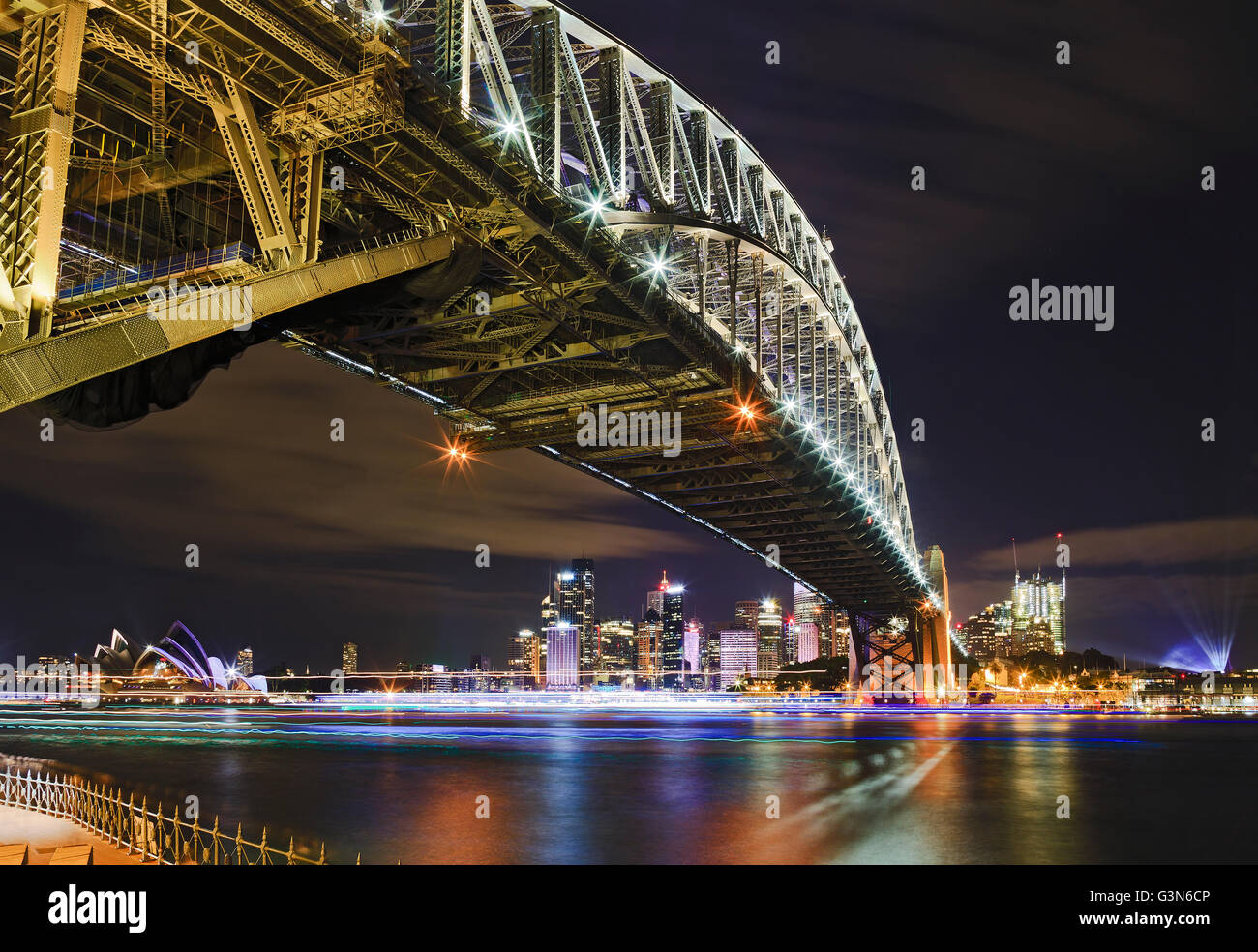 Architectural landmarks of Sydney at dark during light show. Arch of Harbour Bridge above the head towards city CBD and Circular Stock Photo