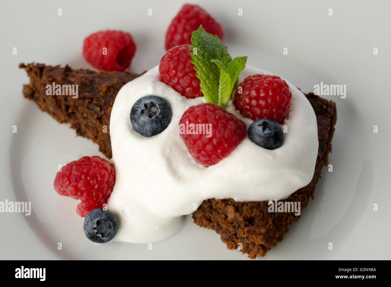 Chocolate cake with raspberries, blueberries and cream Stock Photo - Alamy