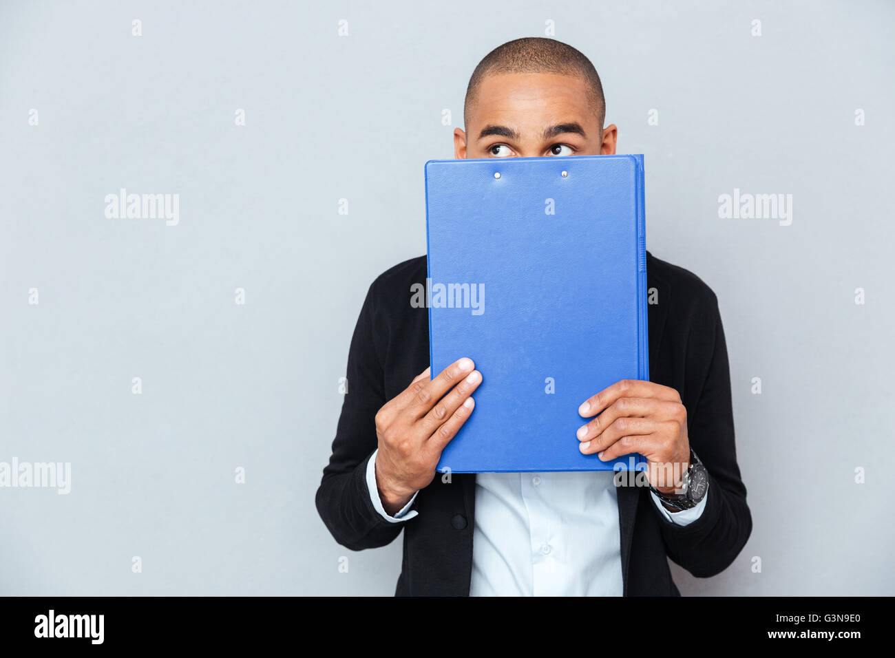 Scared shy african american young man covered his face with blue folder Stock Photo
