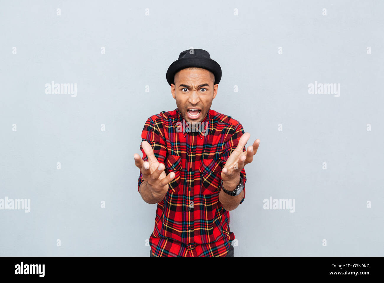 Angry mad african man in plaid shirt standing and shouting Stock Photo