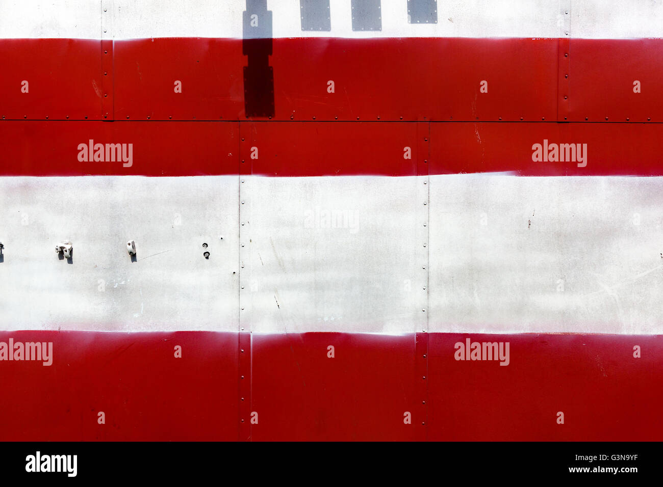 Weathered painted in red and white colors metal panel. Stock Photo