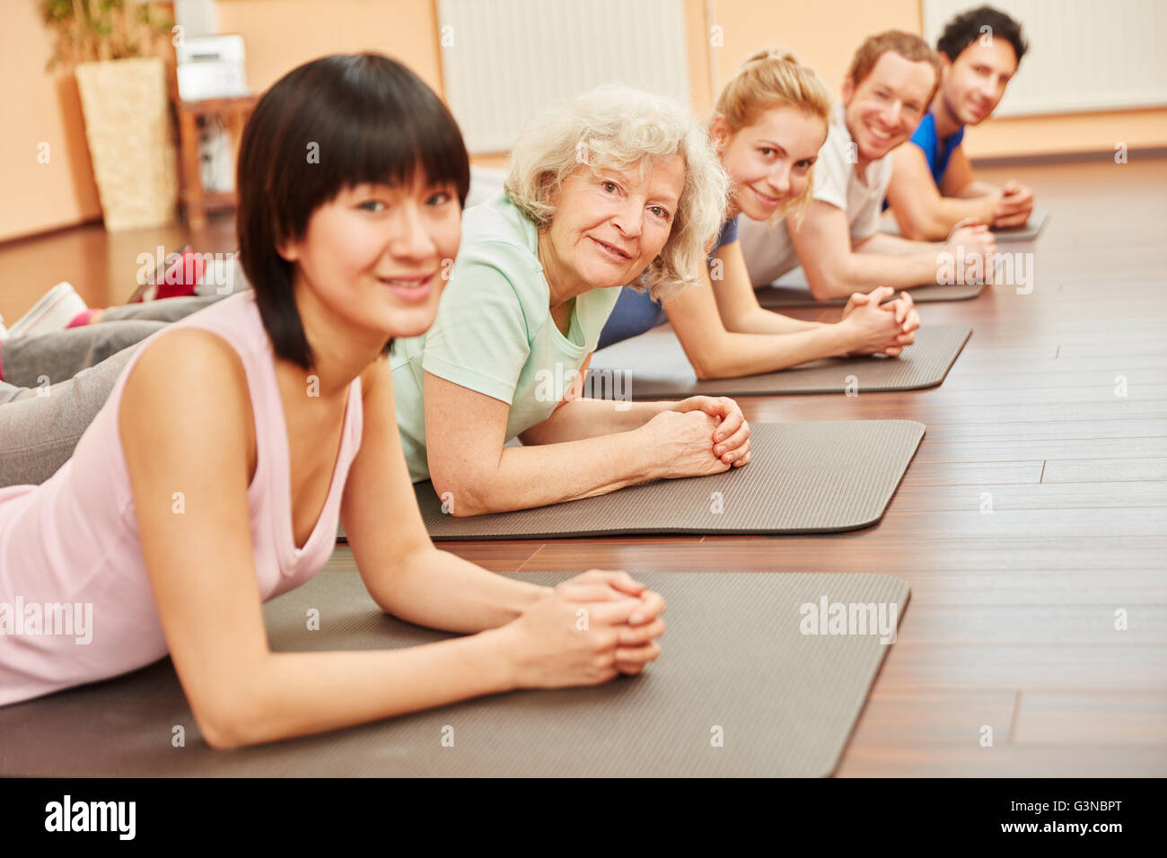 Group in yoga class with senior citizen at health club Stock Photo