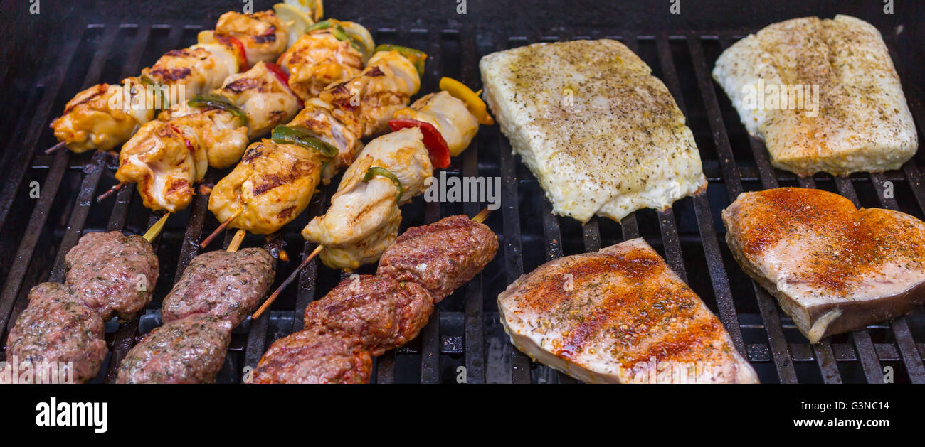 VIRGINIA, USA - Chicken kabobs, lamb kofta skewers, and fish grilling on barbecue. Stock Photo
