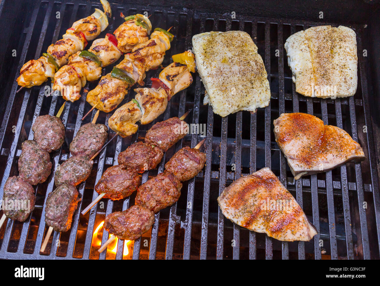 VIRGINIA, USA - Chicken kabobs, lamb kofta skewers, and fish grilling on barbecue. Stock Photo