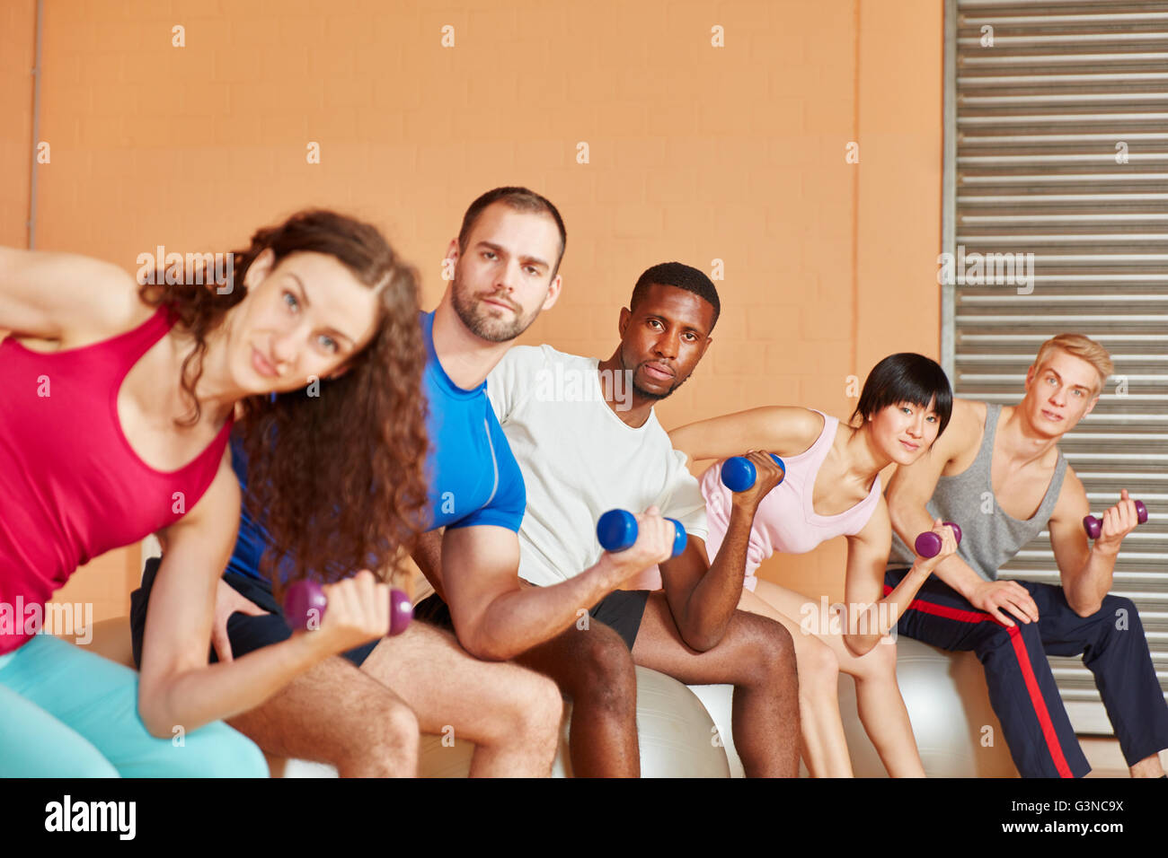 Interracial group training with dumbbells at the gym Stock Photo