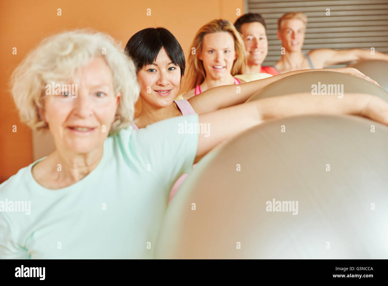 Seniorin making exercise at fitness class with ball Stock Photo