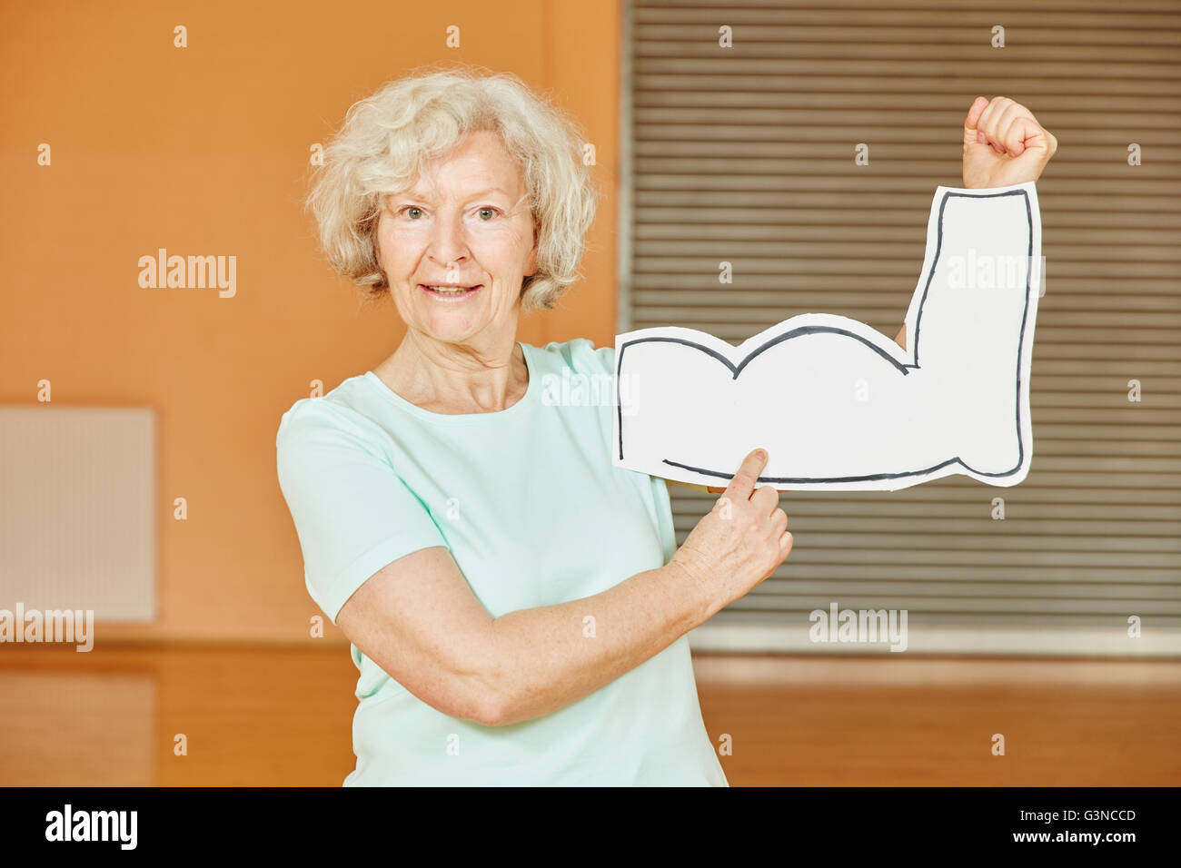 Active Senior with muscles sign at fitness studio Stock Photo