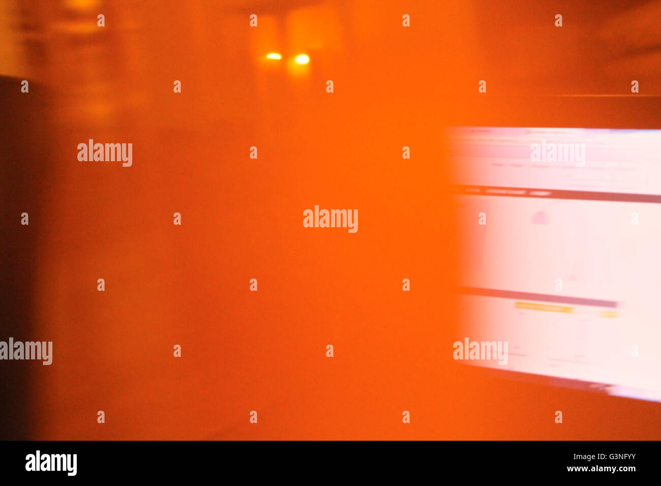 Computer screen with light in background, moving camera and blurred orange Stock Photo