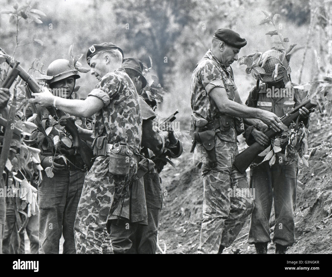 US Green Beret troops train Vietnamese - Instruction in marksmanship with live ammunition is given South Vietnamese native troops by Sgt. Stanley Harold, left, and Capt Robert Lopez of the US Special Forces. Because of the rapid increase of the size of this corps, officers now are assigned on a "non-volunteer" basis, but enlisted men are all still volunteers. Stock Photo