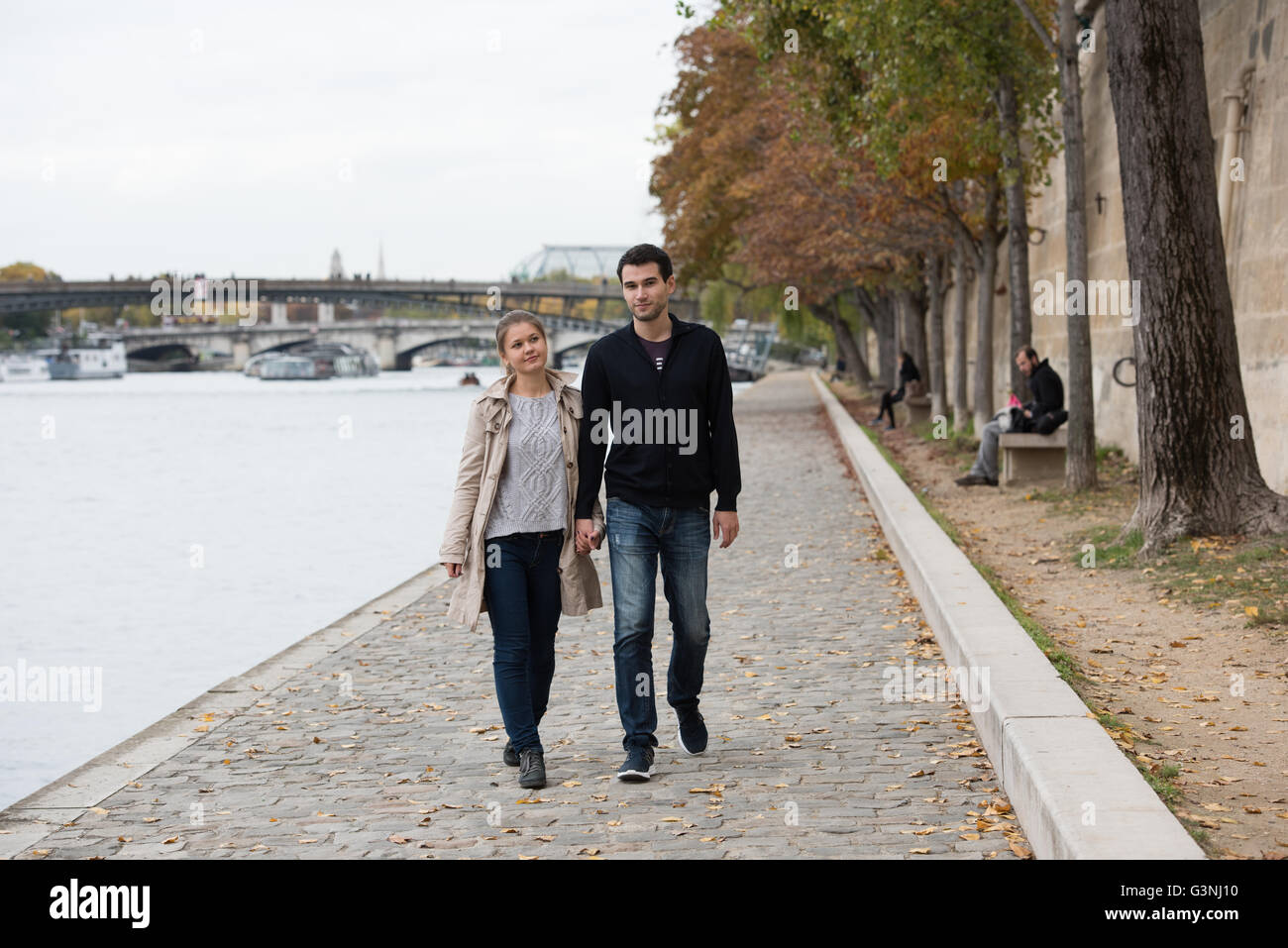 young happy couple man and woman on the riverside of Seine, Paris ...