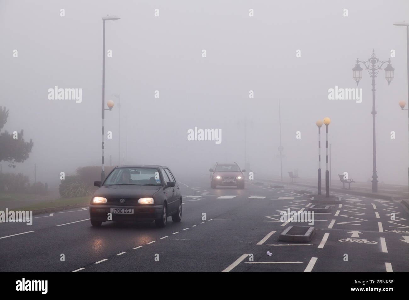 Cars travelling in urban environment with road markings on a foggy day with lights on, Portsmouth, Hampshire, England Stock Photo