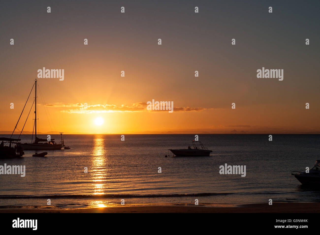 sunset at a beach shore with boats on the water Stock Photo - Alamy