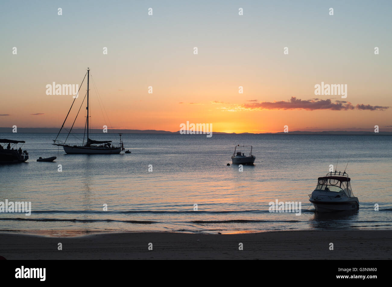 sunset at a beach shore with boats on the water Stock Photo - Alamy