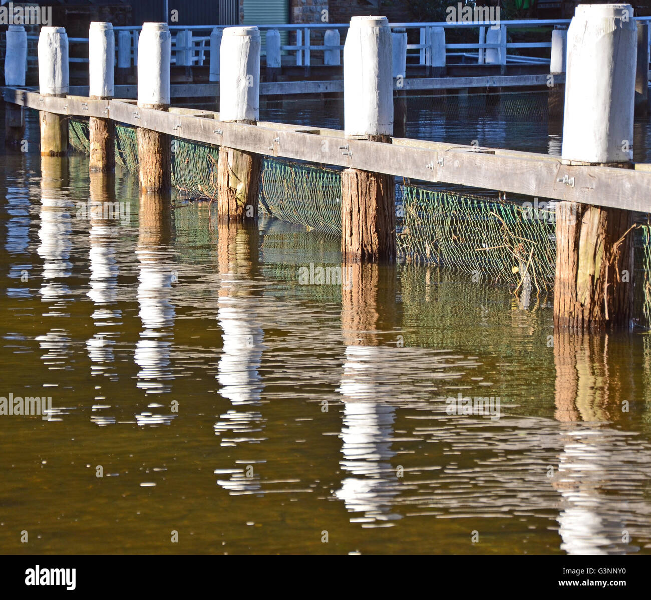 Reflections of wooden pylons in natural swimming baths in a tidal pool ...