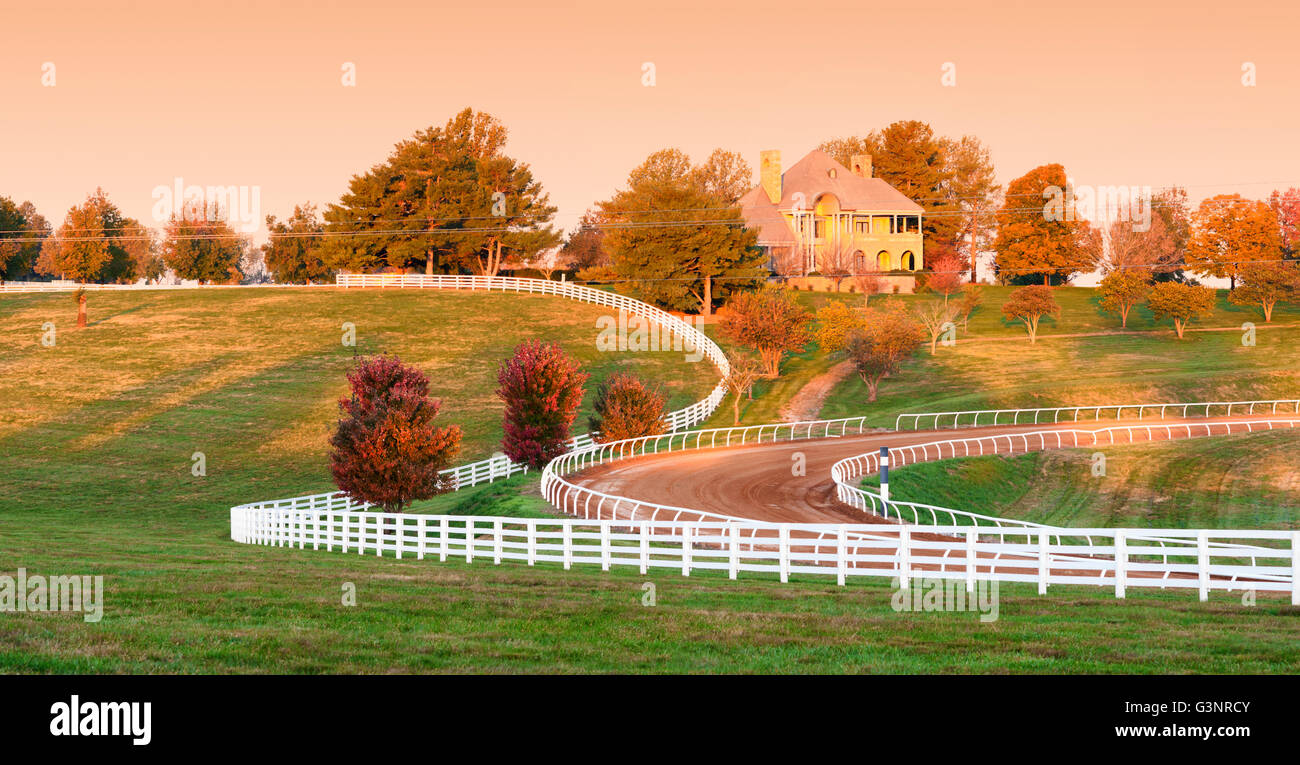 Kentucky horse farm with a white fence curving in front of ...