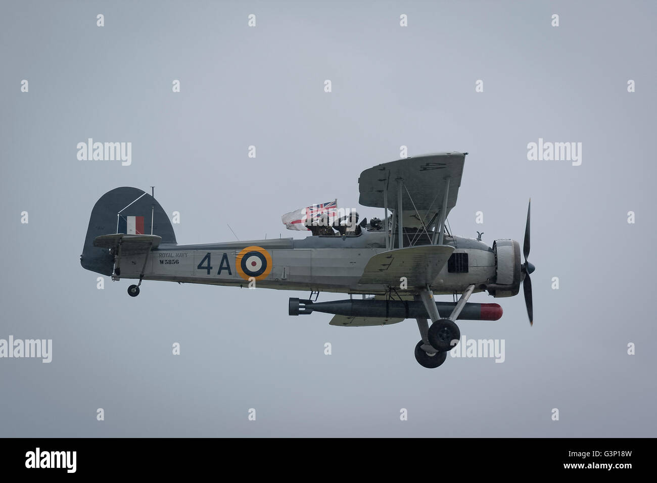 Swordfish fighter plane in flight with air crew saluting and holding up