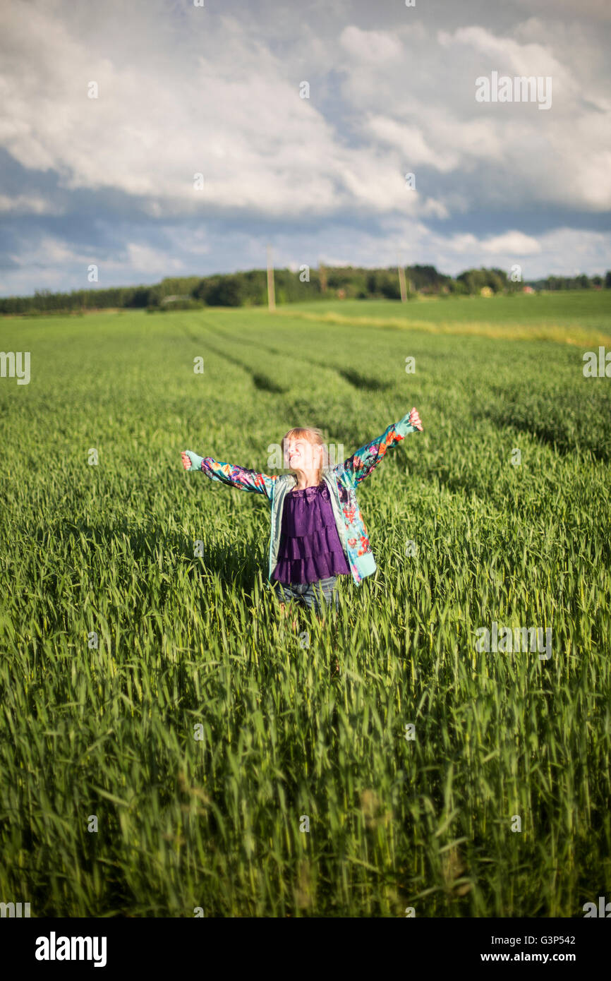 Sweden, Medelpad, Girl (8-9) standing in agricultural field with arms outstretched Stock Photo