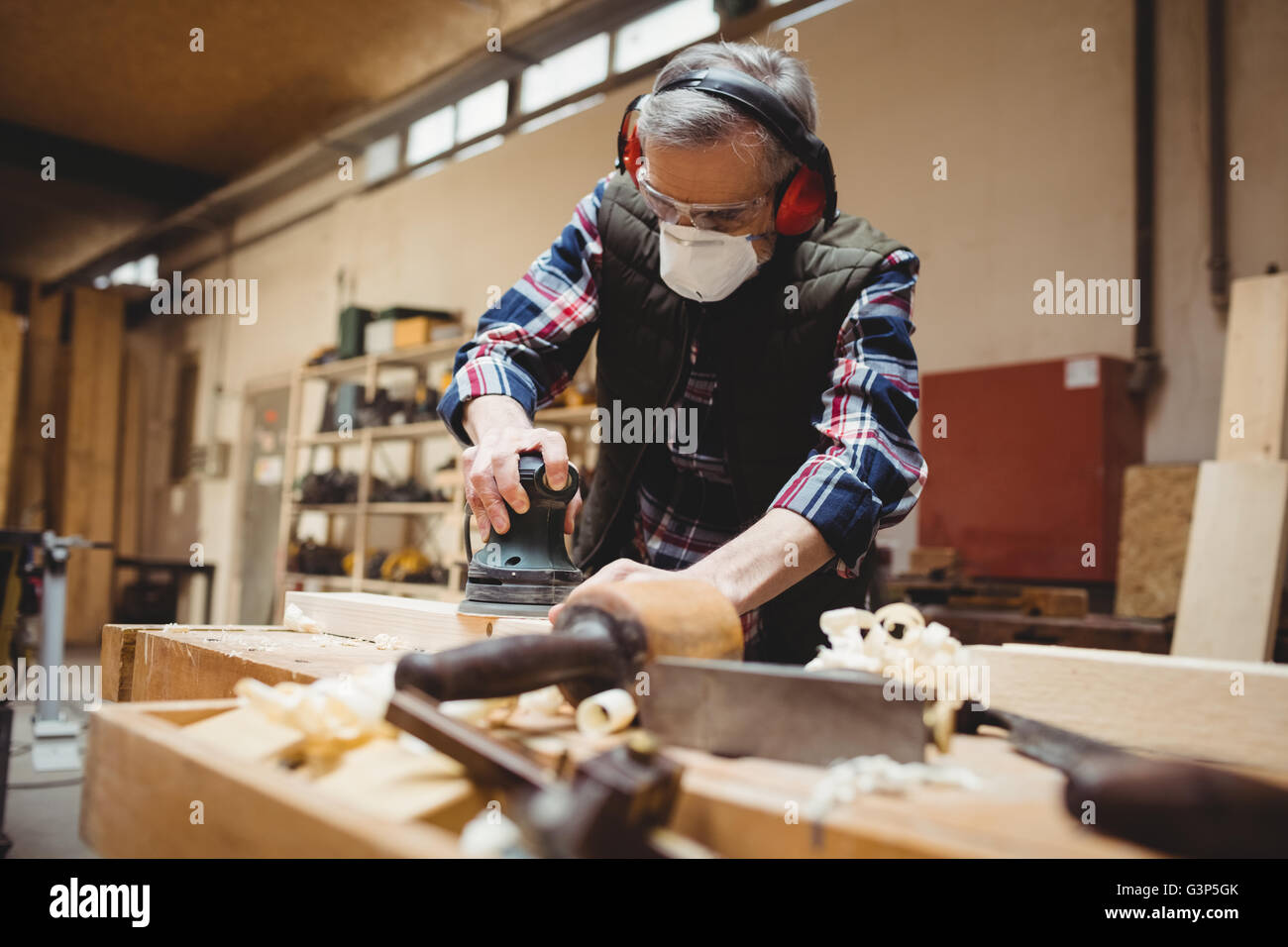 Carpenter sanding down a plank of wood Stock Photo