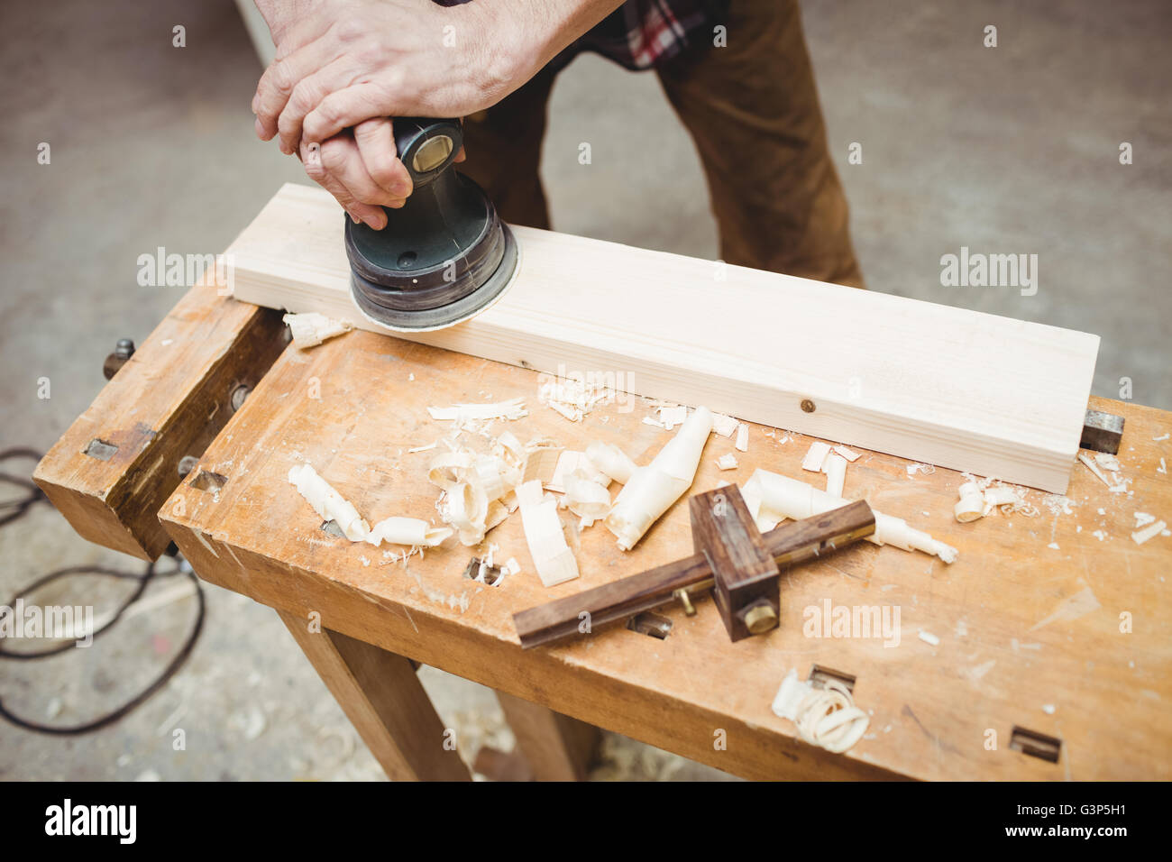 Carpenter sanding down a plank of wood Stock Photo
