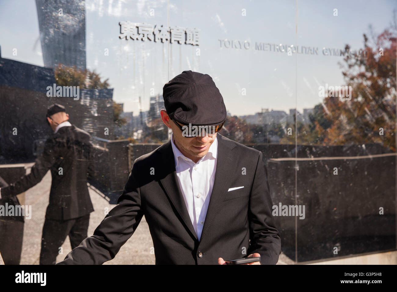 Japan, Tokyo, Shibuya, Man standing outside building, using phone Stock Photo